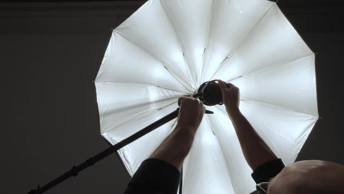 Demonstrating umbrella position adjustment relative to strobe head