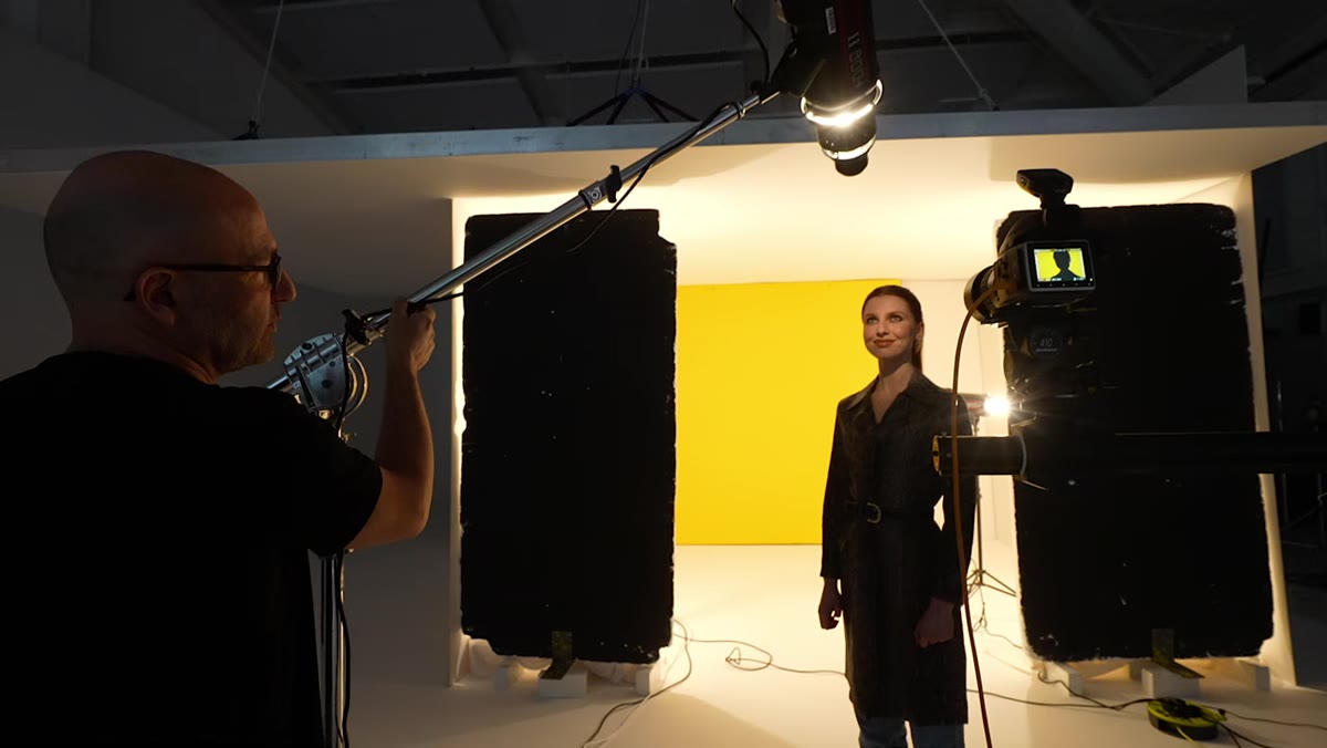 Subject standing in frame with camera and key light visible