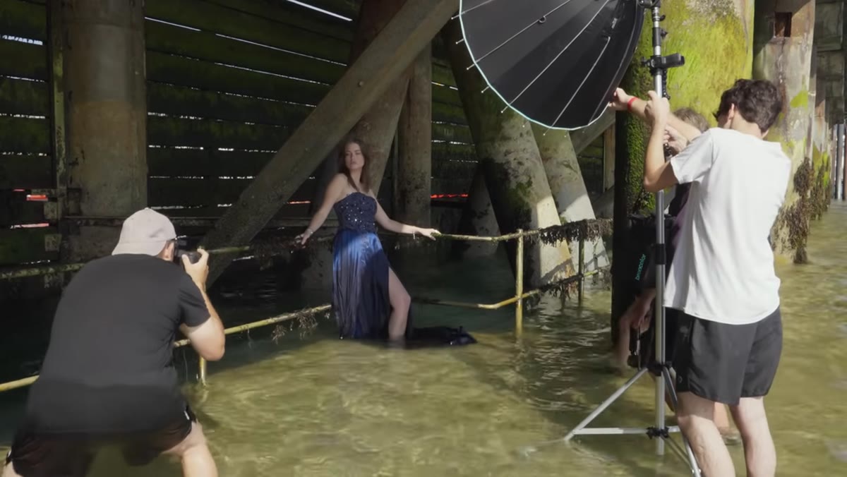 Photographer switching to wide angle lens, directing model to lower position