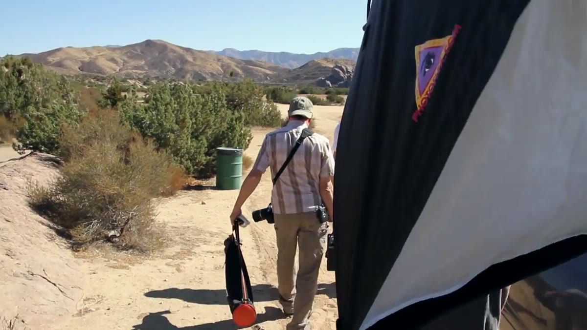 Photographer walking and evaluating rock outcropping and peak background